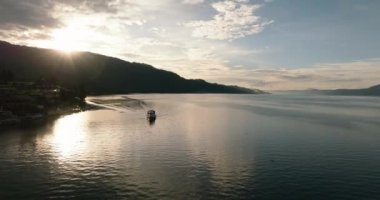 Toba Gölü 'nde güneş ışınlarında küçük bir gemi. Tropik bölgede günbatımı. Sumatra. Endonezya.