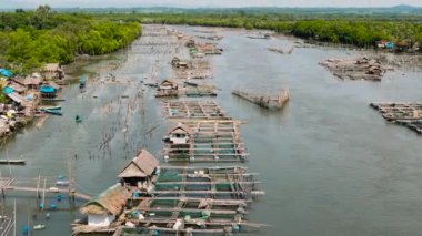 Nehirde kafesleri ve ağları olan balık çiftliğinin havadan görünüşü. Balıkçı köyü Hinigaran Nehri. Zenciler, Filipinler