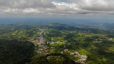 Orman ve yağmur ormanlarıyla dağların arasındaki küçük bir kasabanın en üst görüntüsü. Berastagi, Sumatra. Endonezya.
