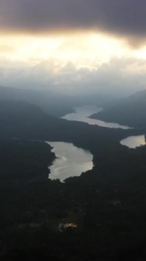 Gün batımında dağların arasında gölleri olan vadinin havadan görünüşü. Kotmale Barajı. Ramboda, Sri Lanka. Dikey video.