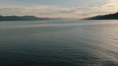 Gün batımında Toba Gölü 'nün su yüzeyinde uçuş. Sumatra, Endonezya.