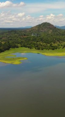 Top view of lake and jungle in the valley against the background of mountains and clouds. Sorabora lake, Sri Lanka.