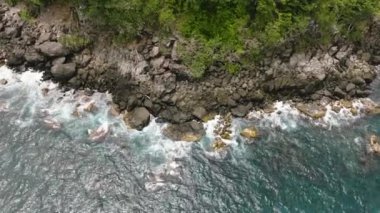 Okyanus dalgaları kayalık kıyıya çarpar. Endonezya.