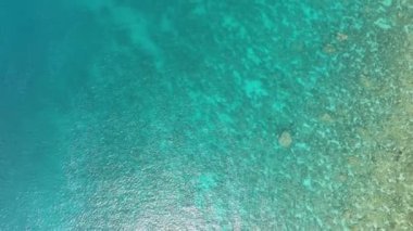 Denizin turkuaz yüzeyinin havadan görünüşü ve güneşin parlaklığı. Şeffaf okyanus suyu yüzeyi.
