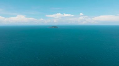 Aerial drone of blue sea and tropical island Apo against blue sky and clouds. Philippines.