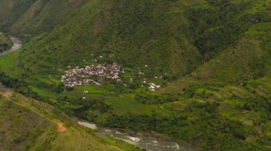 Dağlardaki pirinç teraslarının ve tarlaların arasındaki köyün havadan görünüşü. Filipinler, Luzon.