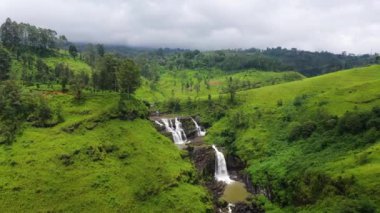 Yeşil tepelerin arasında çay tarlaları olan St. Clair şelalesinin en üst manzarası. Sri Lanka. Çay evi manzarası.