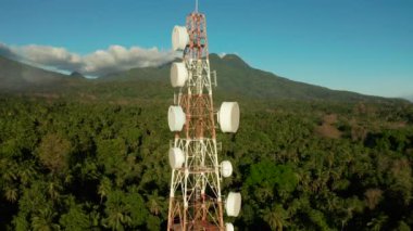 Telekomünikasyon kulesi, dağlara ve yağmur ormanlarına karşı iletişim anteni, hava manzarası. Metal bir kulede tekrarlayıcılar. Camiguin, Filipinler