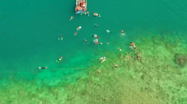 Turistler, açık mavi okyanus suyu ve hava manzarasıyla mercan resifleri üzerinde şnorkelle yüzerler. İnsanlar mercan resifleri arasındaki şeffaf denizde yüzerler. Yaz ve seyahat tatil konsepti.