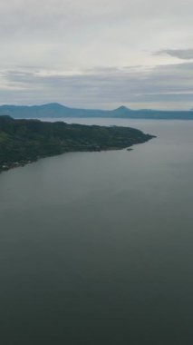 Toba Gölü 'nün ve Samosir Adası' nın havadan görünüşü. Tropik bir manzara. Sumatra, Endonezya. Dikey video.