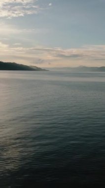 Gün batımında Toba Gölü 'nün su yüzeyinde uçuş. Sumatra, Endonezya. Dikey video.