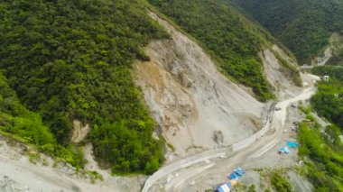 Bir dağ yolunun yapımında kullanılan ağır makinelerin havadan görüntüsü. Çimento yolu toprak kaymasından koruyor.