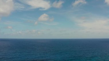 Dalgalı mavi okyanusun yüzeyi ve bulutlu mavi gökyüzü, hava manzaralı. Su bulutu arkaplanı. Gökyüzüne karşı dalgalı mavi deniz suyu.