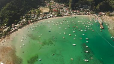 Mavi göl ve turist tekneleriyle körfezdeki El Nido kasabasının hava manzarası. Palawan adasında ünlü bir turistik yer. Mavi körfezli deniz burnu ve yukarıdan görünen tekneler. Yaz ve seyahat