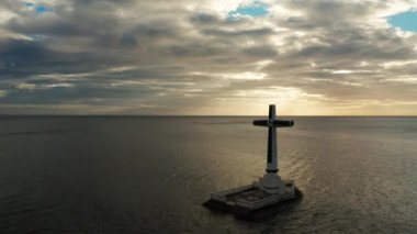 Batık mezarlıkta katolik haçı, gün batımında deniz manzaralı. Batık Mezarlıkta gün batımı Camiguin Adası Filipinleri.
