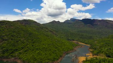 Aerial view of lake among mountains covered rainforest and blue sky with clouds. Kalu Ganga Reservoir, Sri Lanka.