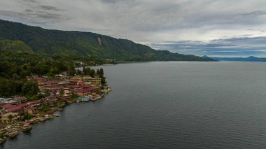 Aerial drone of Tourist spot Tuk Tuk on Lake Toba and the coast of Samosir Island. Sumatra, Indonesia. Tropical landscape. clipart