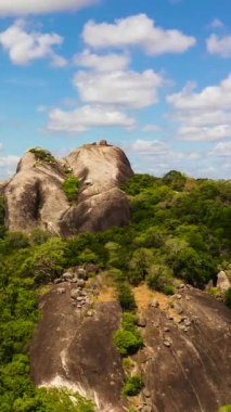 Rocks among the rainforest and jungle against the blue sky and clouds. Sri Lanka, Okanda.