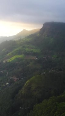 Gün batımında çay evi ve köylerle birlikte dağ yamaçlarının havadan görünüşü. Ramboda, Sri Lanka. Dikey video.