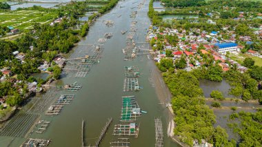 Nehirde balık çiftliği olan bir köy. Hinigaran Nehri. Zenciler, Filipinler