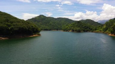 Tropikal bir ormanla dağların arasında bulunan güzel bir göl üzerinde uçuyor. Victoria Barajı, Sri Lanka.