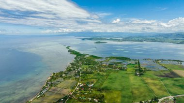 Aerial drone of island coastline with farmland and town. Negros, Philippines.