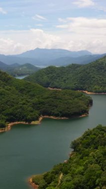 Tropik dağ sırası ve yukarıdan mavi göl manzarası. Victoria Rezervuarı, Sri Lanka. Dikey video.
