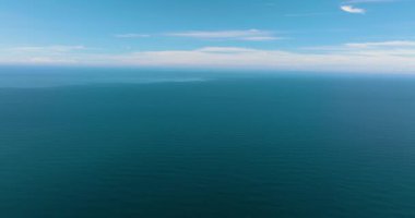 Gökyüzüne ve bulutlara karşı dalgaları olan açık mavi denizin insansız hava aracı. Tropik bölgelerde deniz manzarası. Borneo, Malezya.