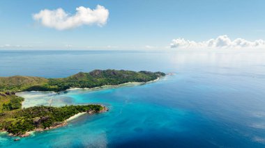 Huzurlu ada, yumuşak dalgalar ve sakin bir ufukla geniş turkuaz denizlere doğru uzanıyor. Curieuse, Seyşeller.