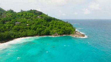 Tropikal bir ada ve bitkilerle ve palmiyelerle çevrili gök mavisi bir deniz. Seyşeller, Mahe.