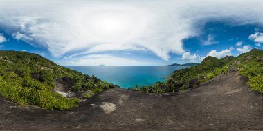 Parlak bir gökyüzünün altındaki yemyeşil tepelere ve engin turkuaz okyanusa bakan bir dağ sırtından çarpıcı bir manzara. Mahe, Seyşeller. 360VR.