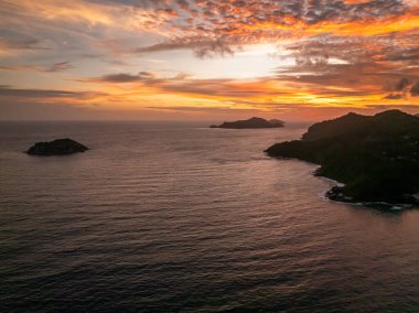 Tropical islands during a colorful sunset over the ocean. Seychelles, Mahe. clipart