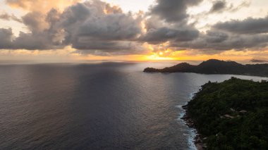 Mahe kıyı şeridinde gün batımı kara bulutlar, sakin okyanus suları. Seyşeller, Mahe.
