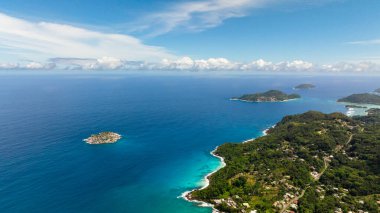 Geniş okyanus manzarası, uzak adalar ve parlak mavi gökyüzünün altındaki turkuaz sular. Seyşeller, Mahe.