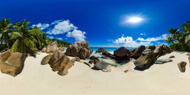 Parlak bir güneşin altında turkuaz sulara yuva yapmış, yüksek palmiye ağaçları ve pürüzsüz dev kayaları olan gizli kumlu bir sahil. Anse Patates. La Digue, Seyşeller. VR 360.
