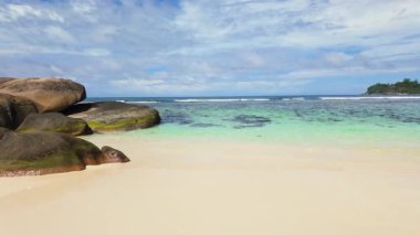 Büyük granit kayaları, turkuaz suyu ve mavi gökyüzü olan tropik bir sahil. Seyşeller, Mahe.