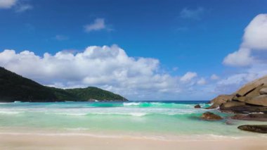 Temiz turkuaz suyu ve parlak gökyüzünün altında yemyeşil tepeleri olan el değmemiş bir sahil. Polis Körfezi. Seyşeller, Mahe.