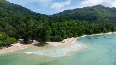 Turkuaz suları ve yemyeşil yemyeşil, tepeler ve açık gökyüzüyle çevrili bir sahil. Seyşeller, Mahe. Anse Marie Louise.