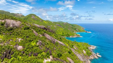 Uçsuz bucaksız mavi okyanusla çevrili kayalık kıyıları olan yeşil adaların havadan görünüşü. Seyşeller, Mahe.