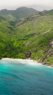 Orman dağları ve açık deniz arasına kurulmuş kumsalı olan bir koy. Seyşeller, Mahe. Anse Du Riz plajı. Baie Ternay Deniz Ulusal Parkı.
