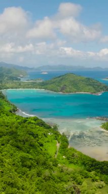 Turkuaz koyları olan kıyı manzarası, yemyeşil tepeler ve bulutlu bir gökyüzünün altındaki uzak adalar. Seyşeller, Mahe.