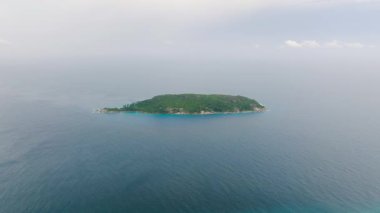 Gökyüzü altında engin mavi deniz ile çevrili yeşil ada. Seyşeller, Gebe Kalma Adası.