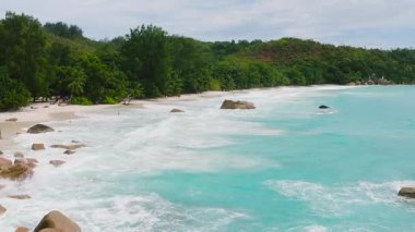 Kıyı boyunca büyük granit kayalar üzerine dalgalar çarpıp köpük oluşturur. Anse Lazio. Seyşeller, Praslin.