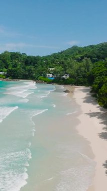 Sahil boyunca temiz su ve yemyeşil tropikal bitki örtüsüyle beyaz kumlar. Seyşeller, Mahe. Grand Anse Sahili.