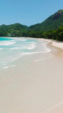 Plaj boyunca uzanan altın kumlar, yemyeşil tropikal bitki örtüsüyle sınırlıdır. Seyşeller, Mahe. Grand Anse Sahili.