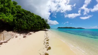 Temiz turkuaz suyu, yumuşak kumu ve kıyı boyunca yoğun yeşil yaprakları olan güzel bir tropikal plaj. Seyşeller, Praslin.