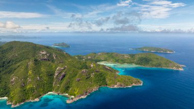 Ormanla kaplı dik tepeler derin mavi okyanus, görülebilir uzak adalar. Seyşeller, Mahe.