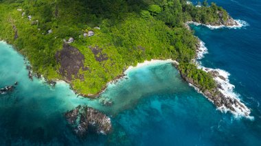 Beyaz kumlu, kayalık bir sahil şeridi boyunca yeşil bitki örtüsü. Seyşeller, Mahe. Butzel Sahili.