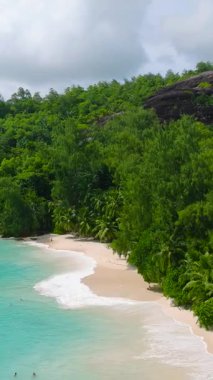 Turkuaz suları ve ince beyaz kumları olan tropikal bir plajın çevresindeki yeşil bitki örtüsü. Seyşeller, Mahe. Anse Soleil Plajı.