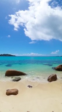 Beyaz kumlu el değmemiş bir sahil, yükselen granit kayalar ve ufka uzanan bir turkuaz okyanus. Seyşeller, Praslin. Anse Takamaka.